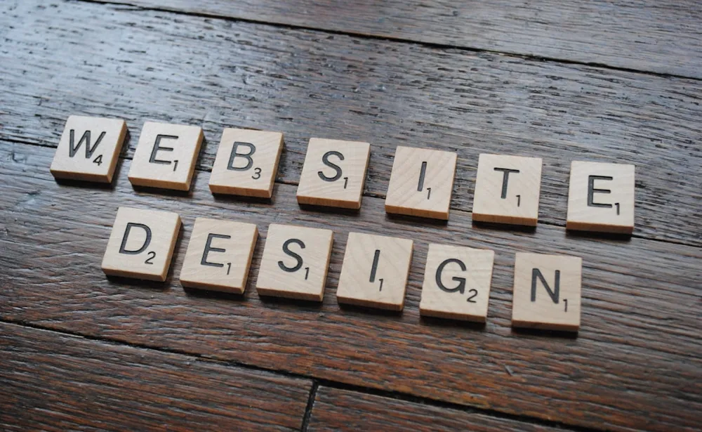 Scrabble-brikker, der staver 'WEBSITE DESIGN' på en træoverflade.