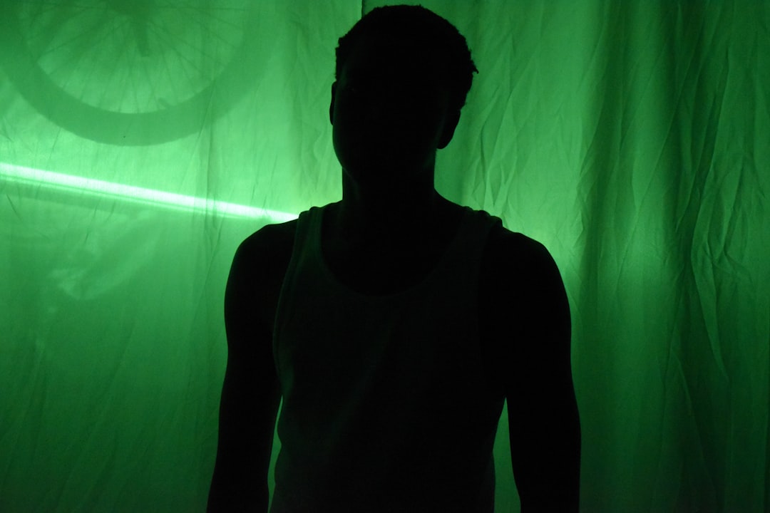 Silhouette of a person against a green backlit curtain.
