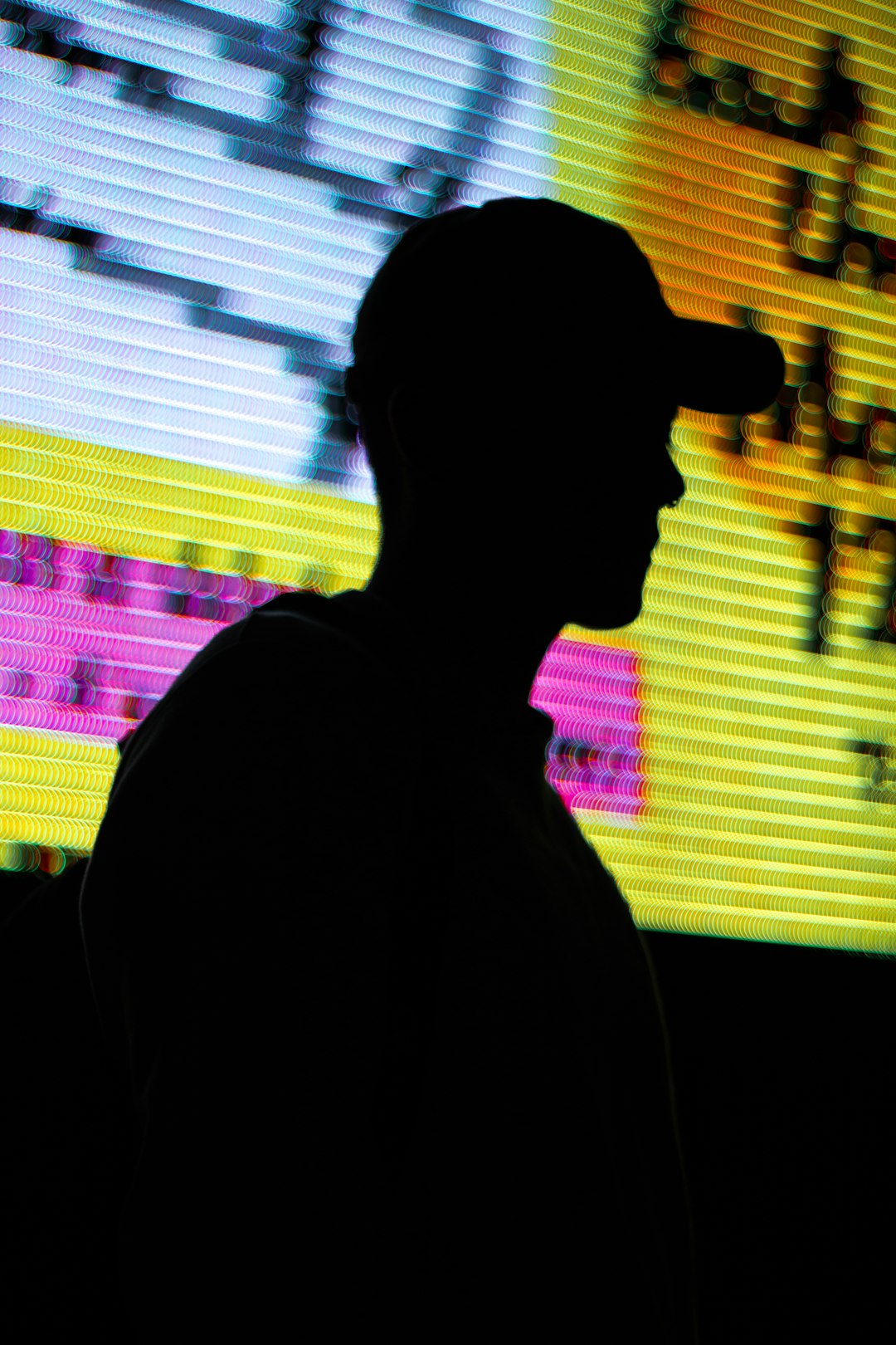 Silhouette of a person in front of a colorful LED screen.