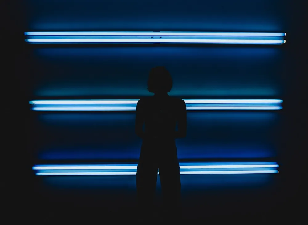 Silhouette of a person standing in front of blue neon lights.