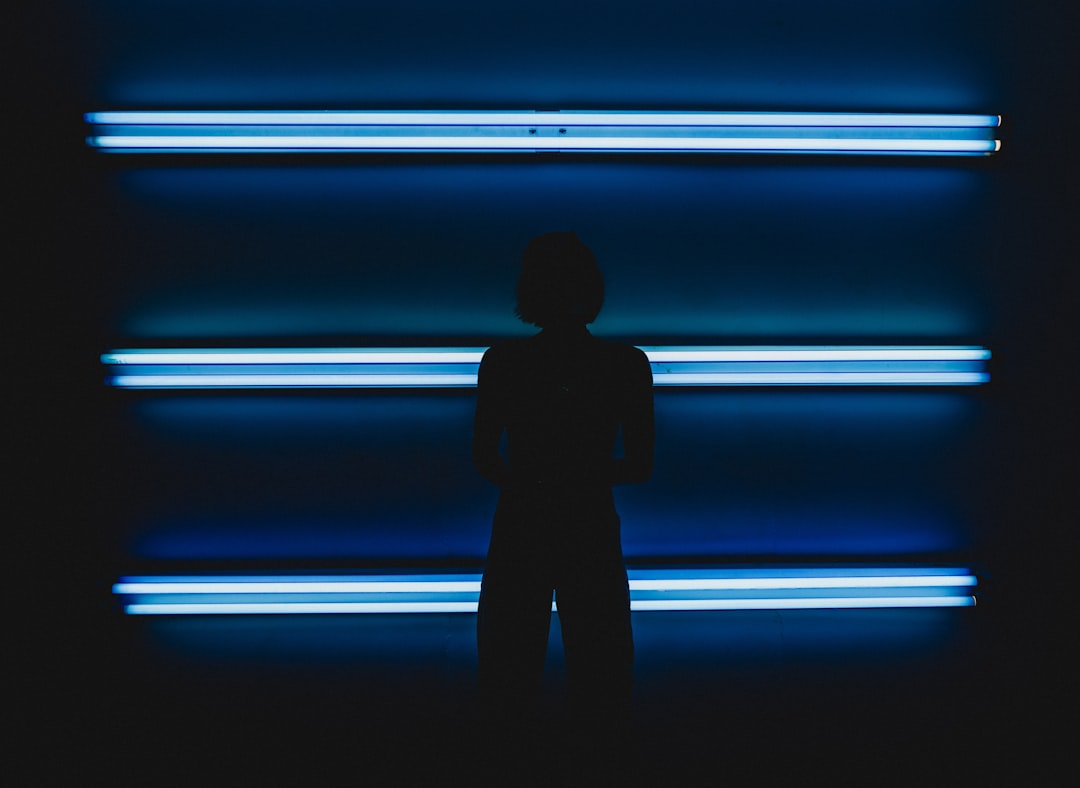Silhouette of a person standing in front of blue neon lights.