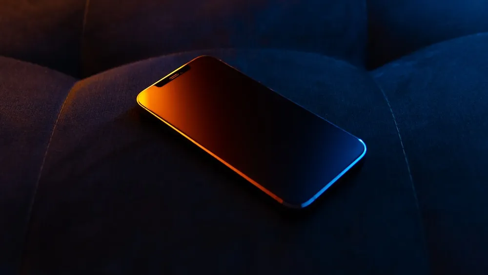 Smartphone on a dark surface with colorful lighting.