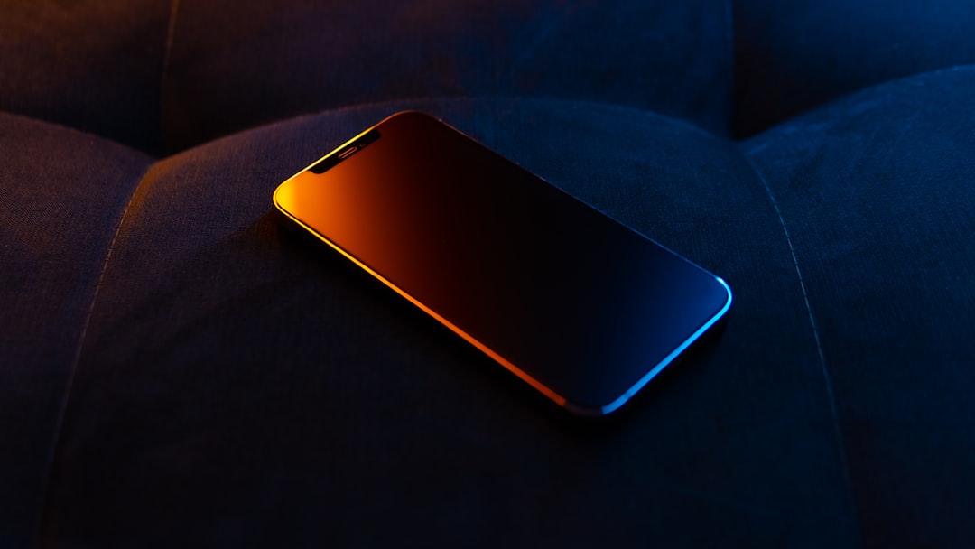 Smartphone on a dark surface with colorful lighting.