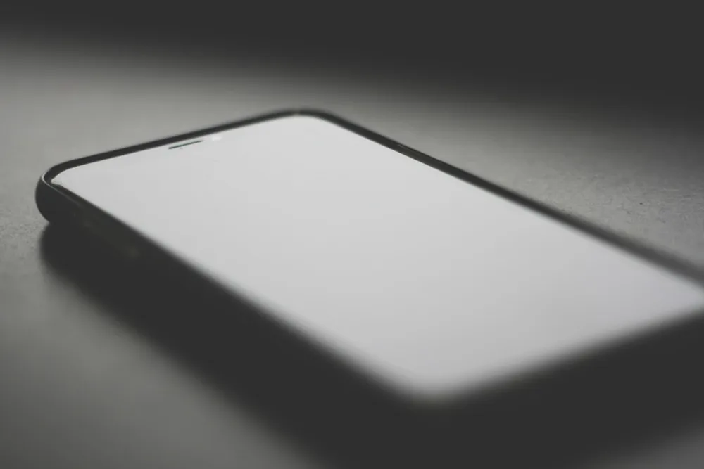 Smartphone with a blank screen on a dark surface.