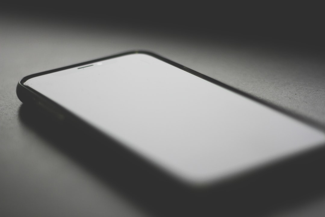 Smartphone with a blank screen on a dark surface.