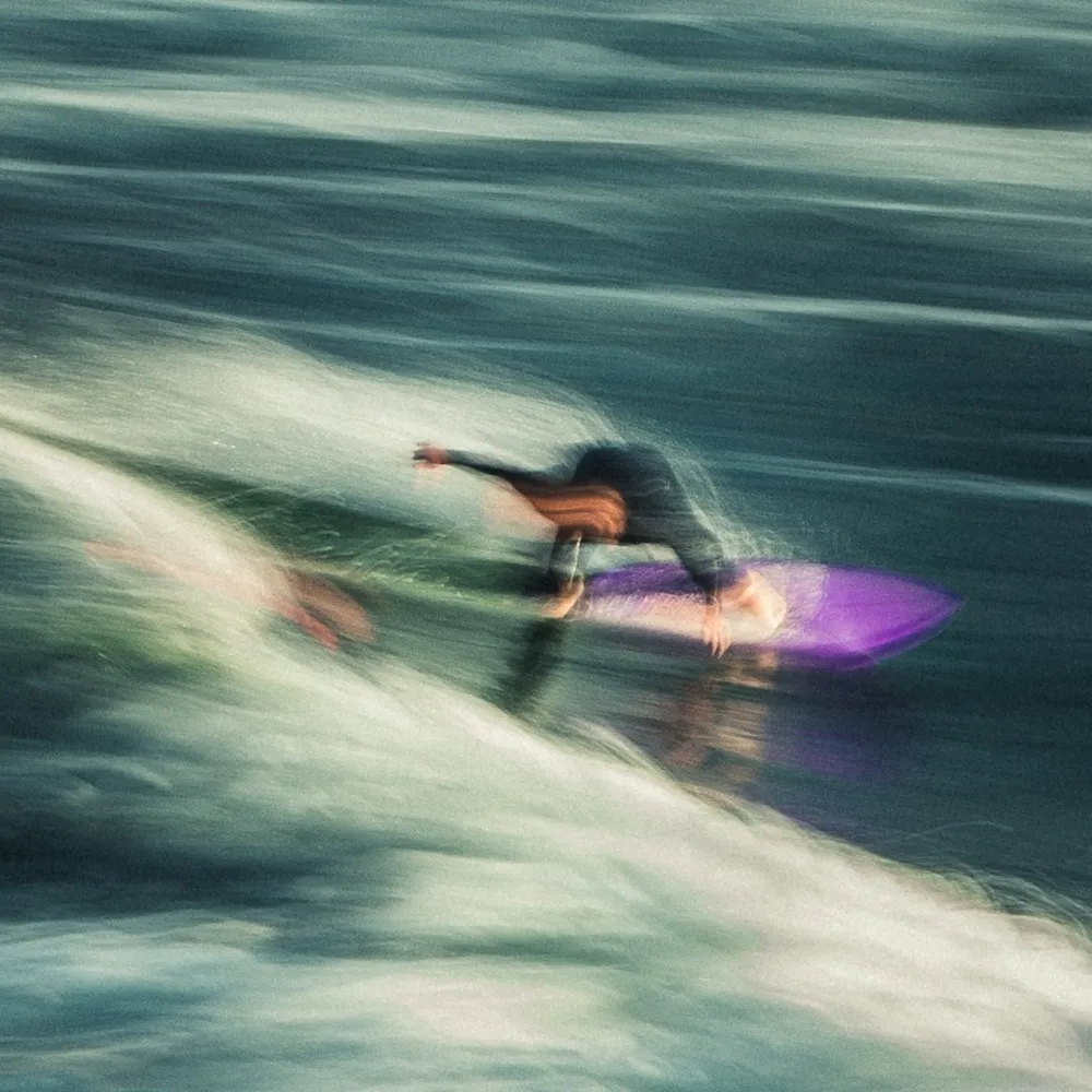 Surfer riding a wave with motion blur.