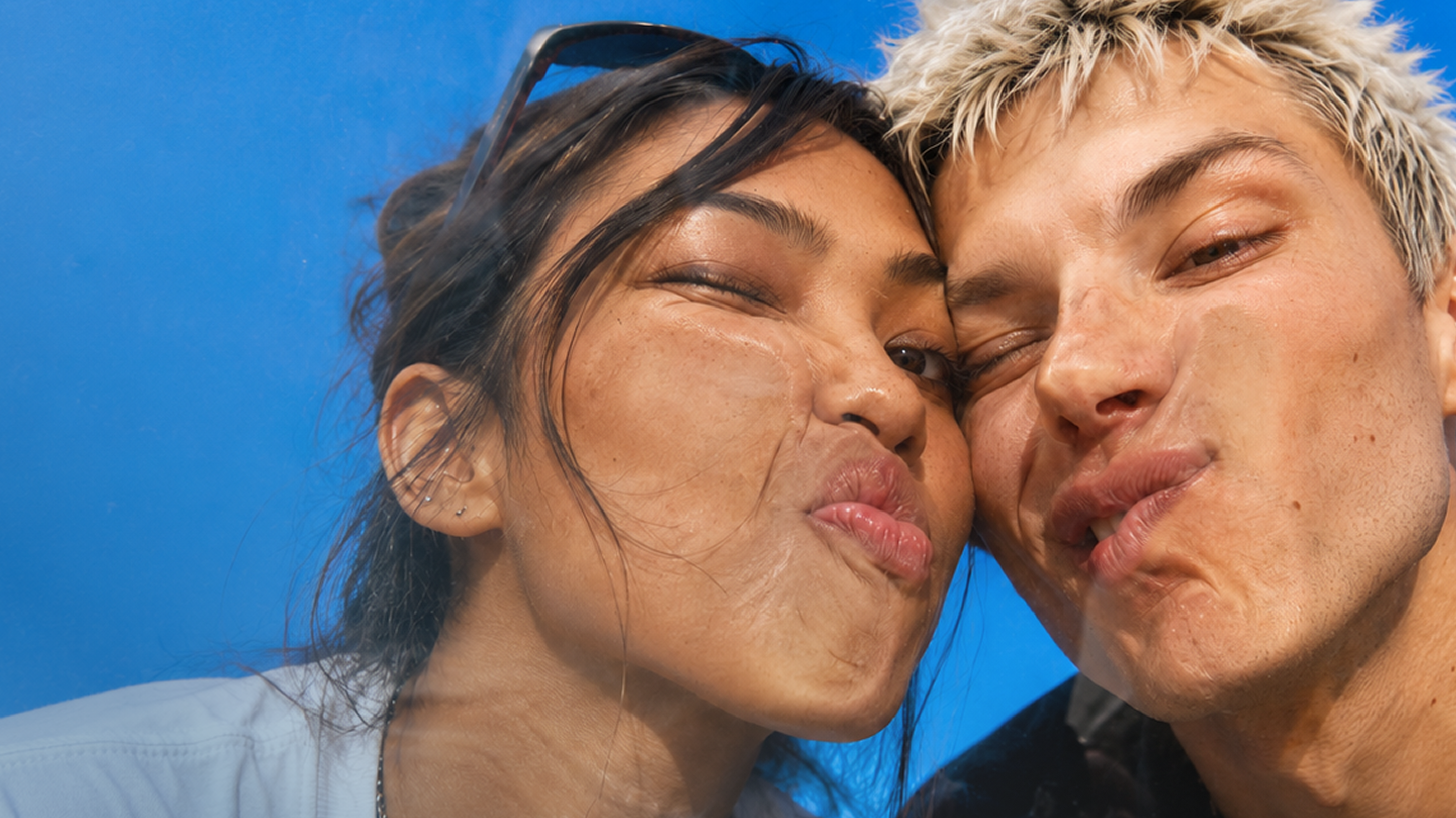 Two people pressing their faces against glass with a blue background.