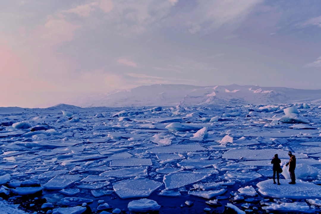 Two people standing on ice in a vast icy landscape.