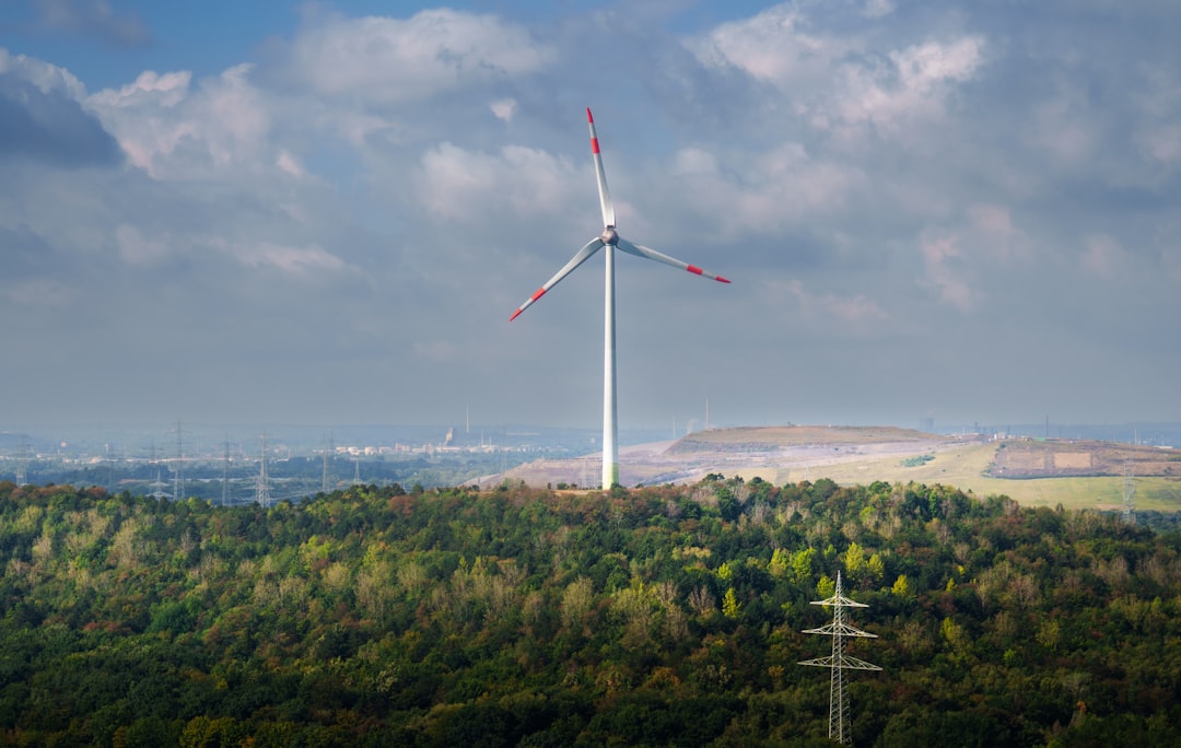Wind turbine on a hill with a cloudy sky.