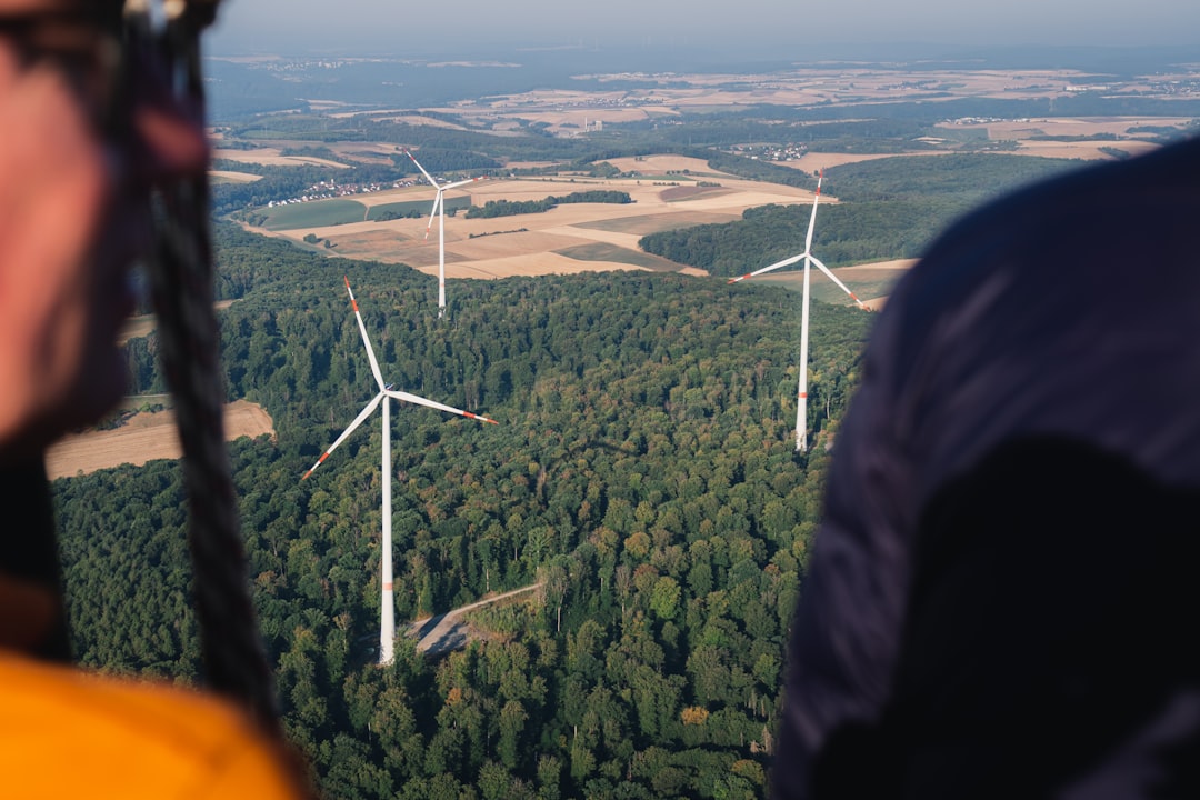 Wind turbines in a forested landscape viewed from above.