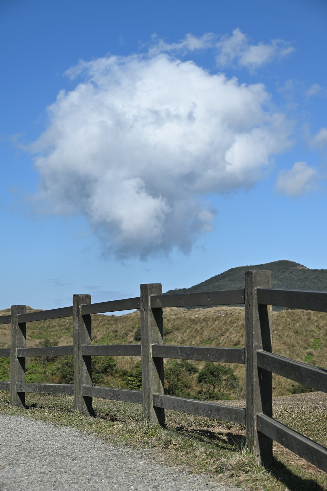Wooden fence with a large cloud in the sky.