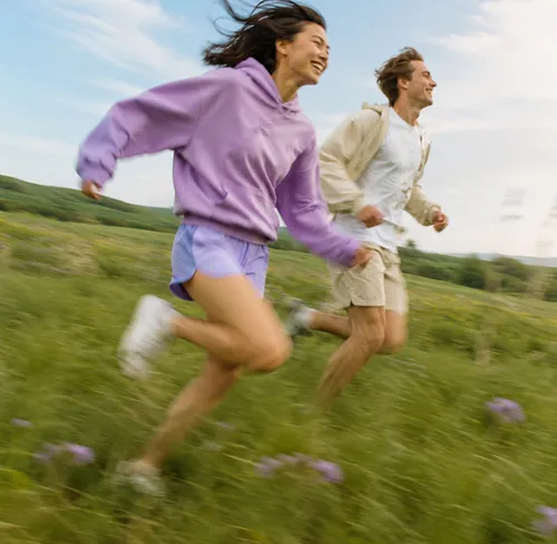 Two people walking across a green meadow.